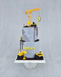 A birthday cake with a construction theme, decorated with toy construction vehicles and caution signs.