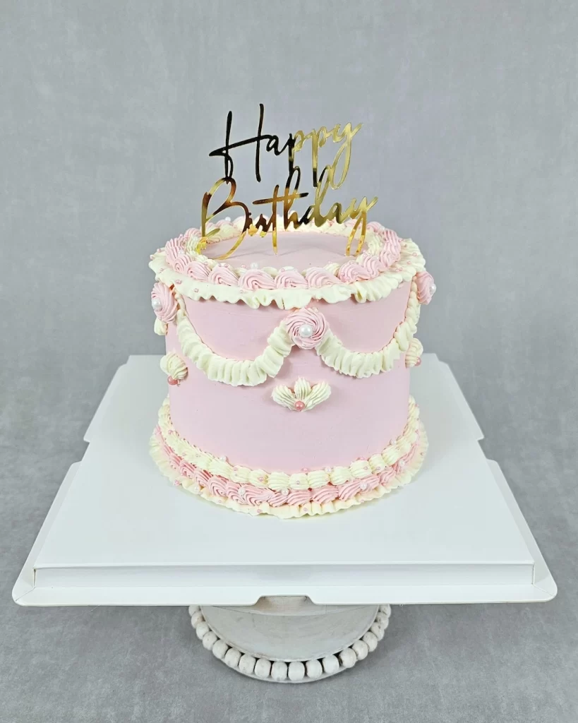 Pink birthday cake decorated with elegant buttercream designs